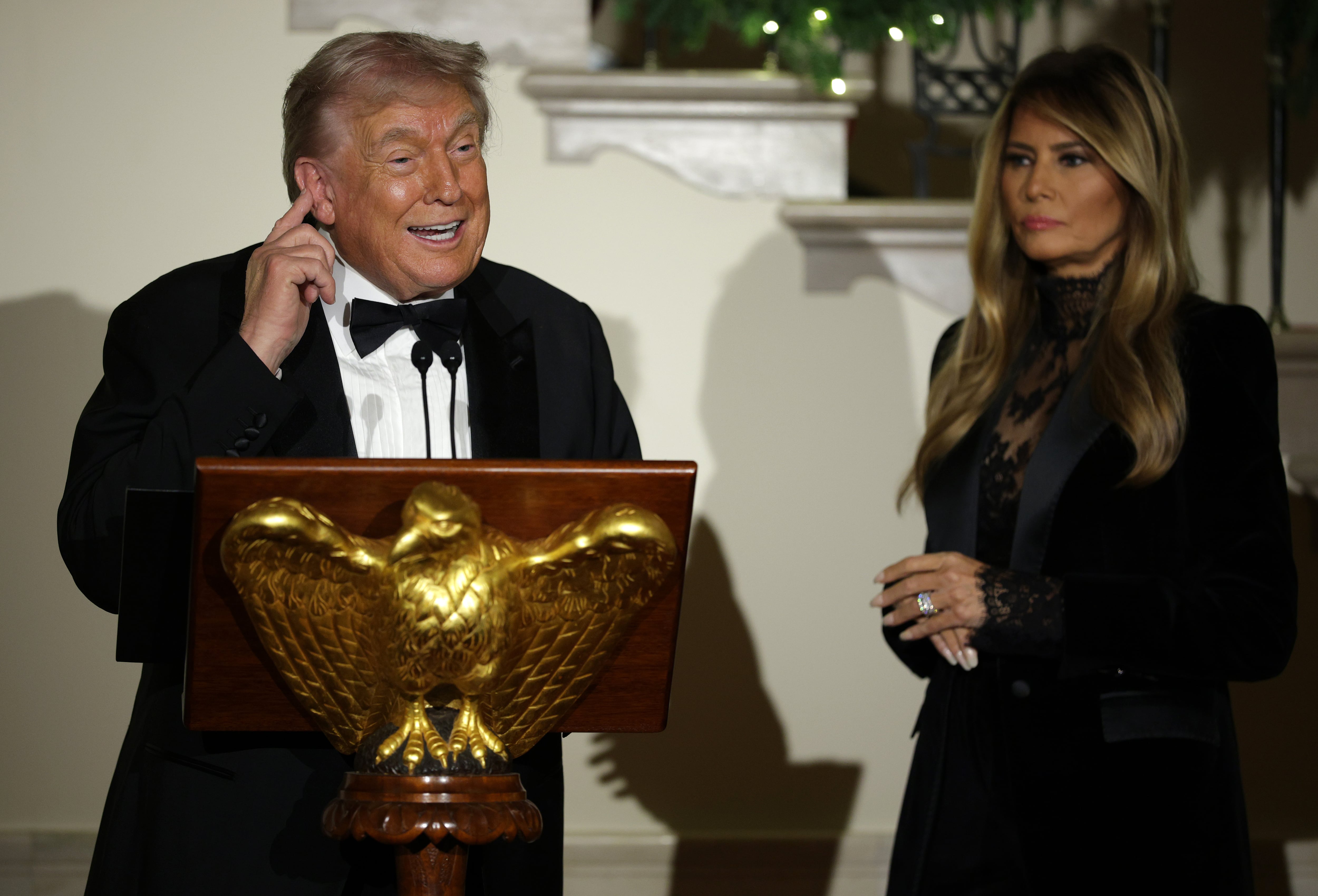 U.S. President Donald Trump (L) delivers remarks as First Lady Melania Trump (R) looks during the Congressional Ball at the Grand Foyer of the White House on December 11, 2025 in Washington, DC. President Trump hosted congressional members at the White House to celebrate the holiday season. / Alex Wong / Getty Images